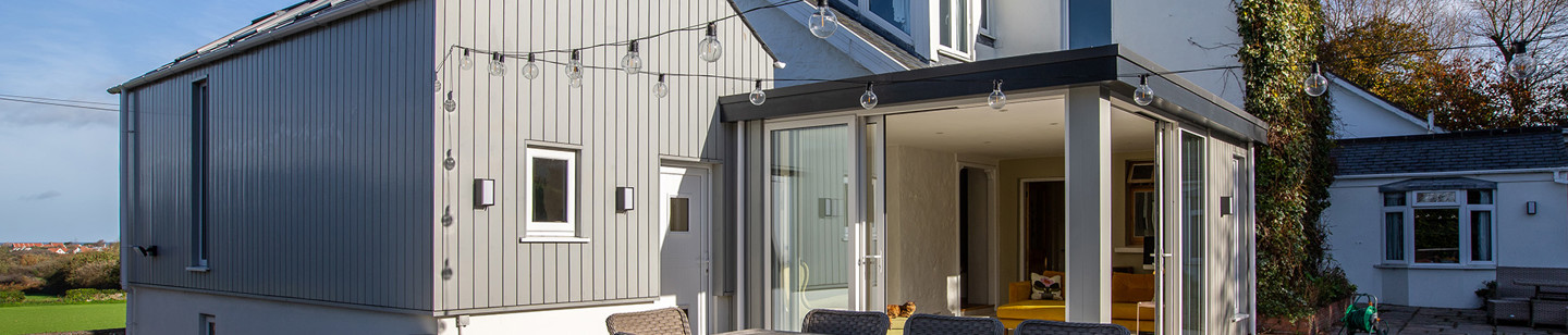 Property with a large patio, festoon lights, table and chairs, and a conservatory