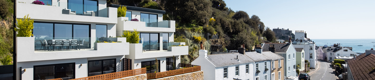 Houses along Le Mont Gabard in Jersey, showcasing a variety of architectural style, including one modern among more tradtional designs