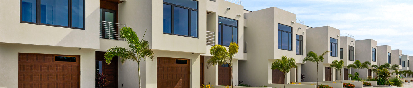 Row of houses each with a garage entrance and palm tree